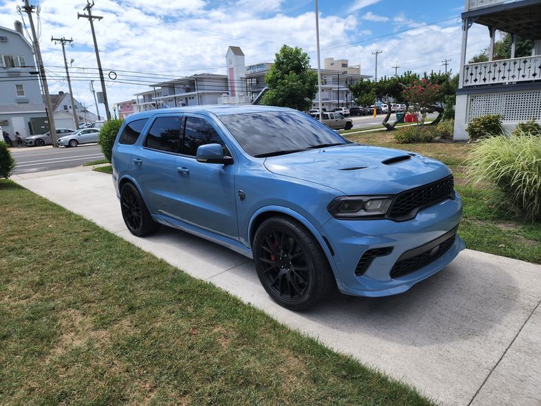 Blue SUV parked on a sidewalk beside a grassy verge in a residential neighborhood
