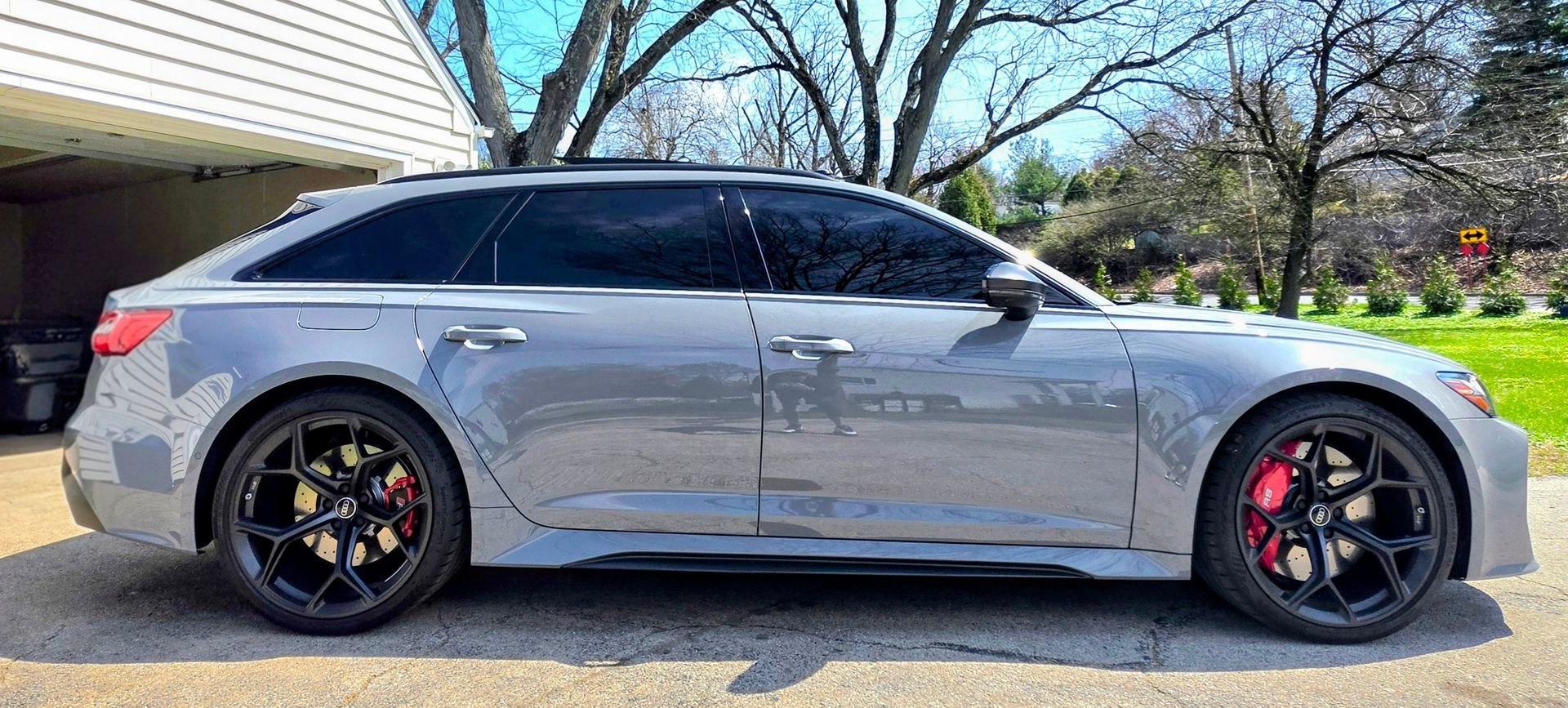 Silver sports sedan parked in a driveway, side view, with black rims and red brake calipers.