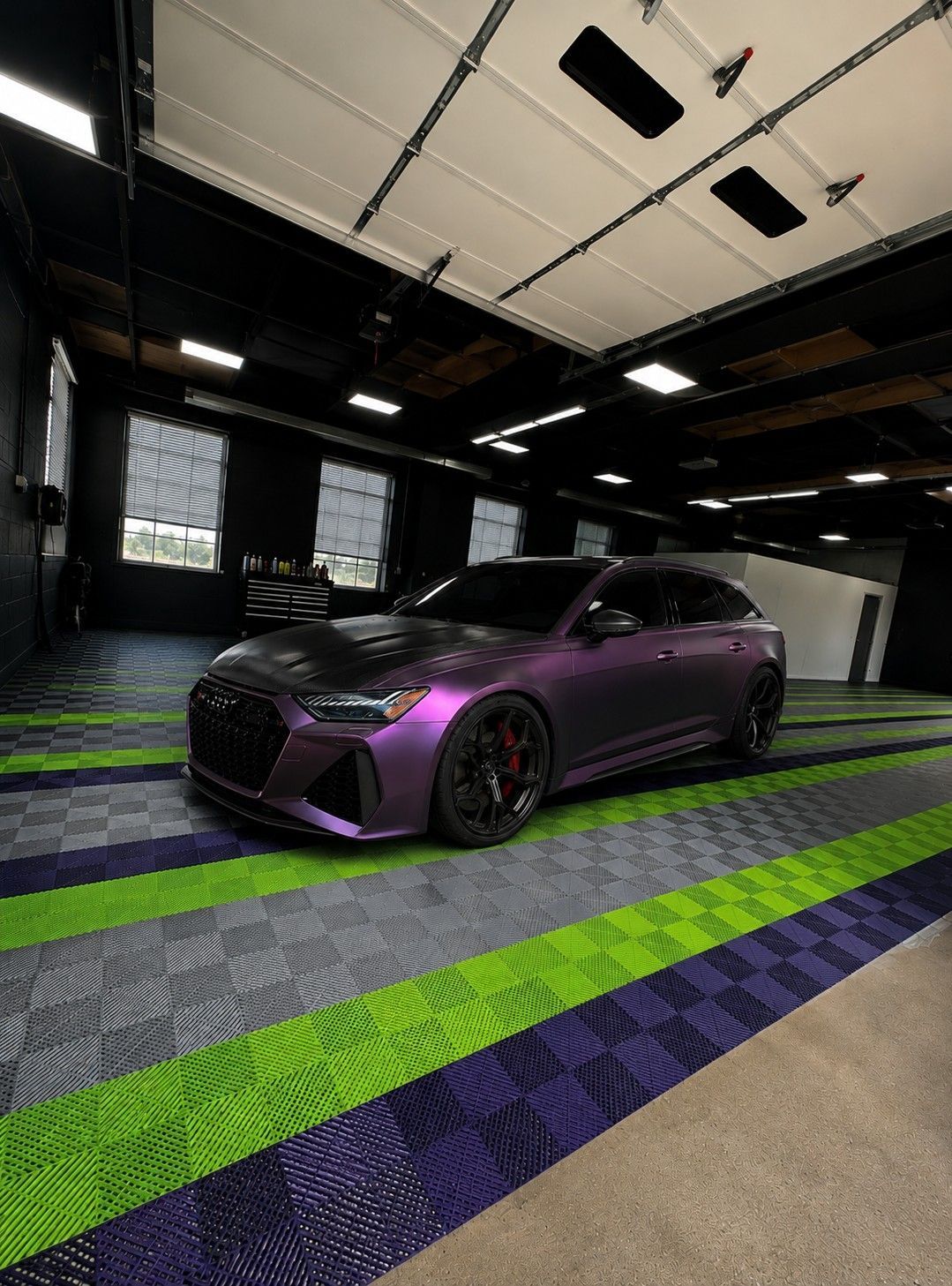 Purple sports car in a dim garage with neon green floor stripes