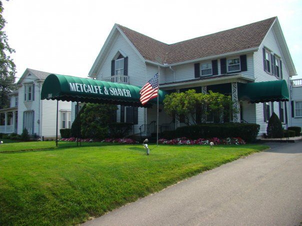 a white house with a green awning that says wetcalf & shaver