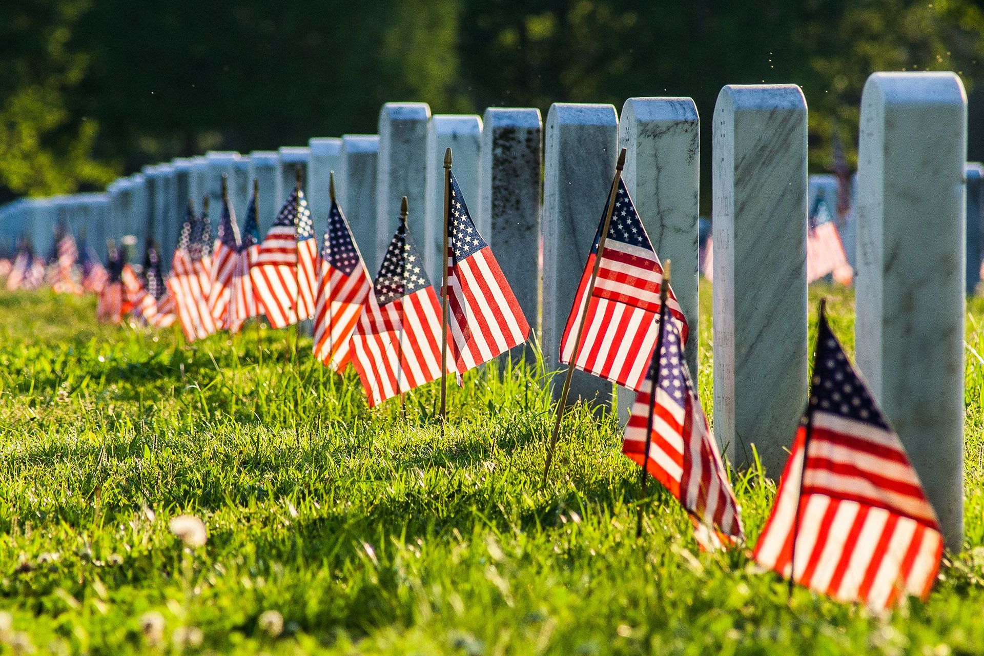 a row of graves with american flags in front of them
