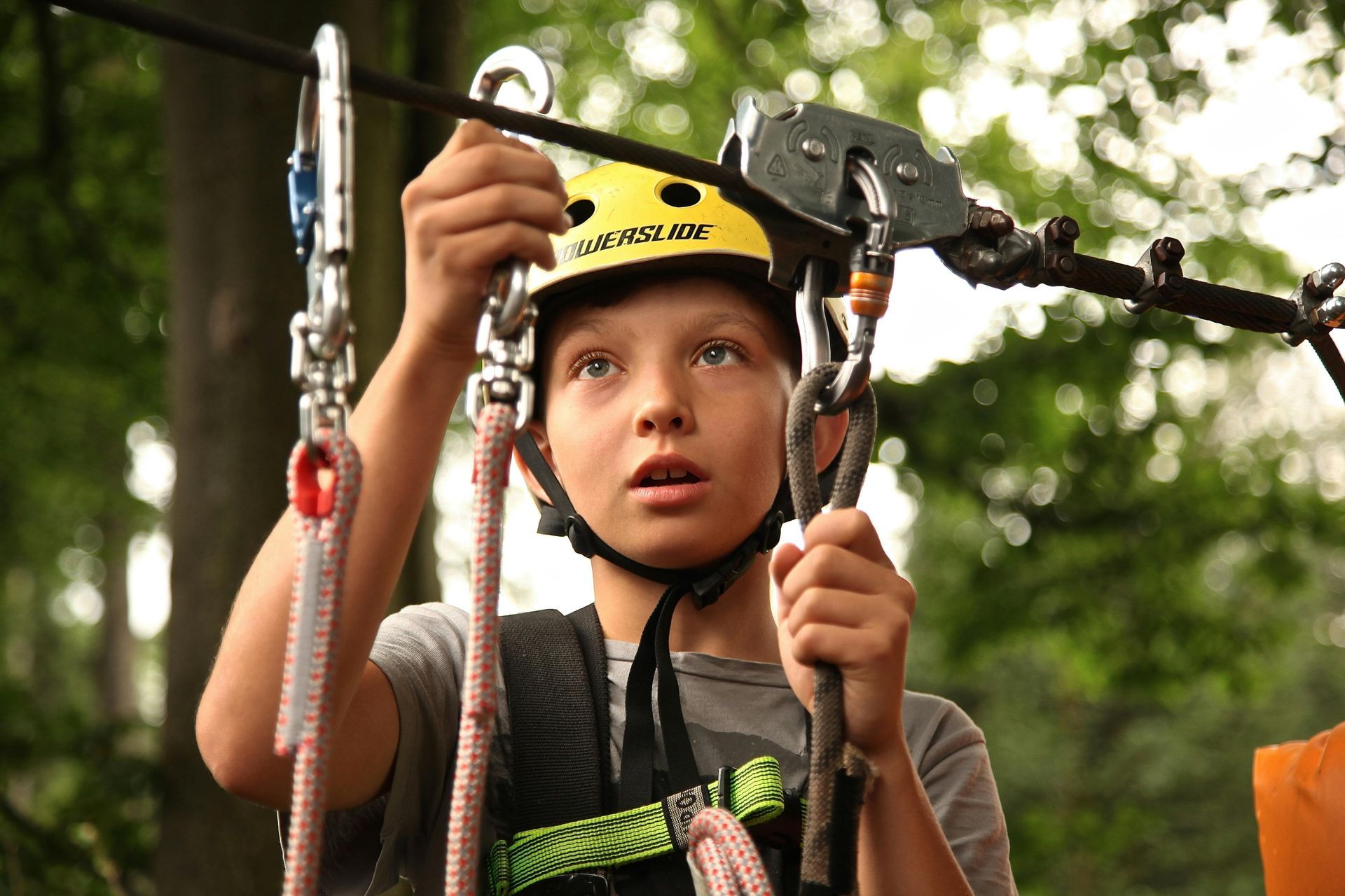 a young boy clipping his zip line on a rope