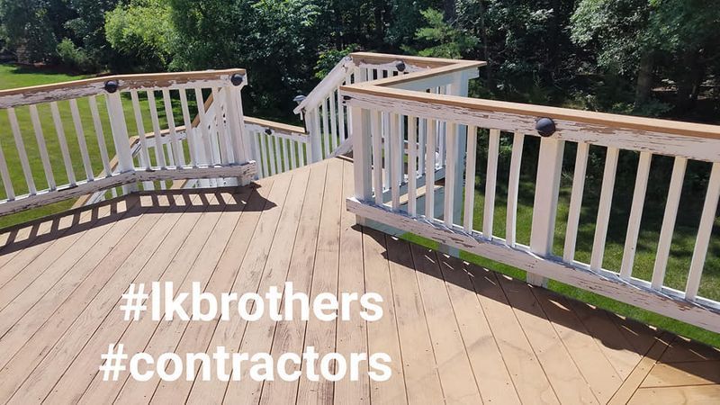 Wooden deck with white railings overlooking a green yard, with hashtag text