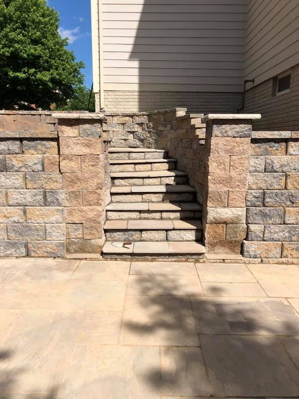 Stone steps between retaining walls lead up to a house exterior.