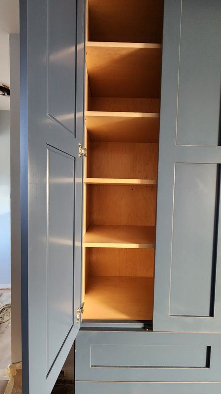 Open closet with white doors and warm-lit wooden shelves inside