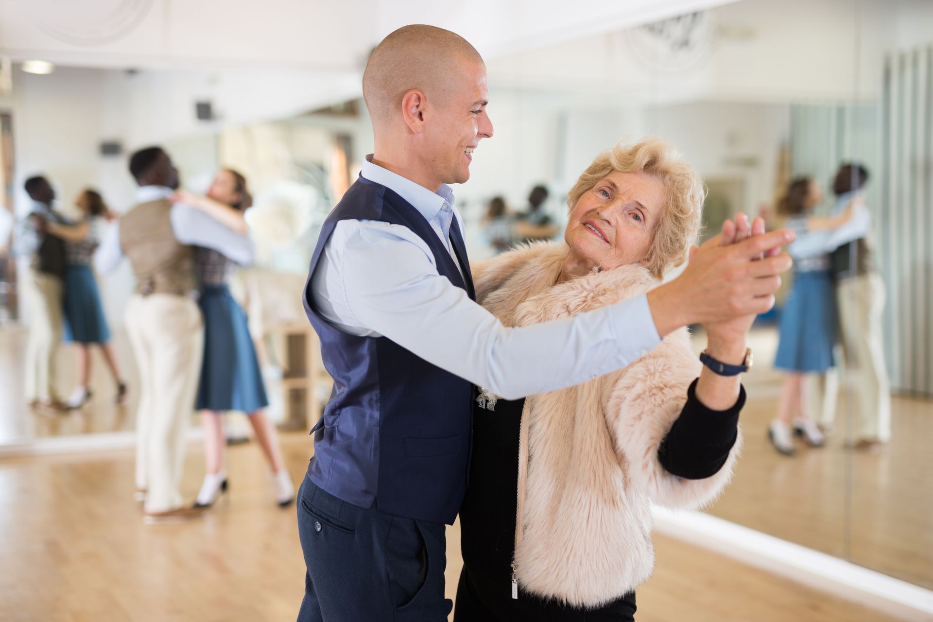 Elderly woman learns ballroom dance steps with partner, improving gracefully.