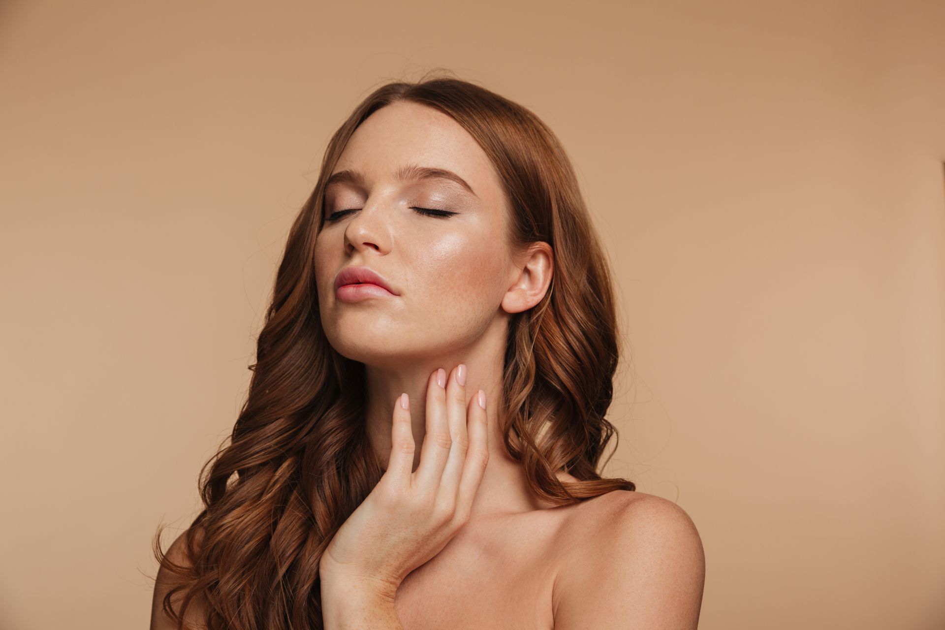 Woman with closed eyes gently touching her neck against a beige background
