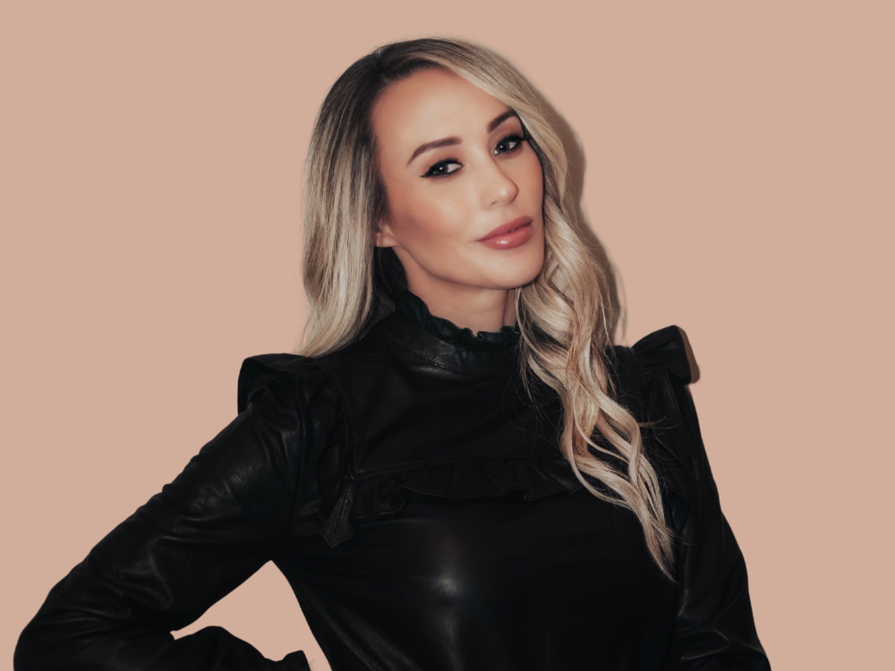 A woman with blonde hair is wearing a black leather jacket