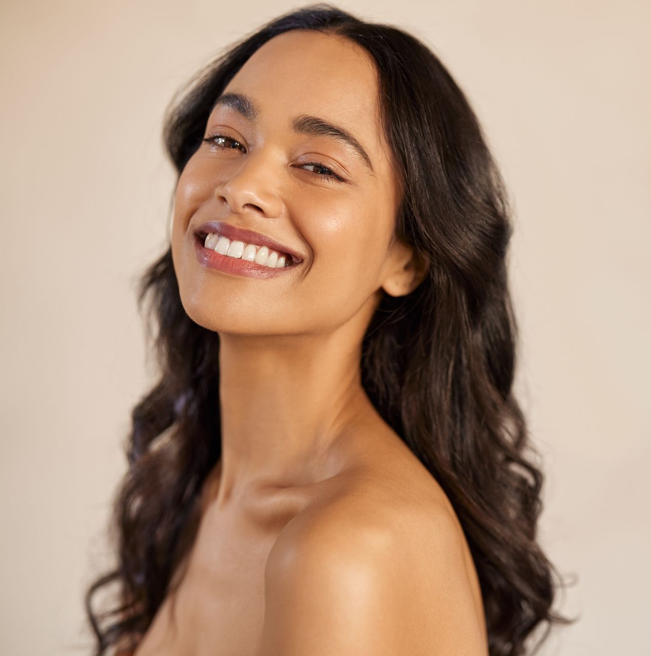 A woman with long hair is smiling and looking at the camera.