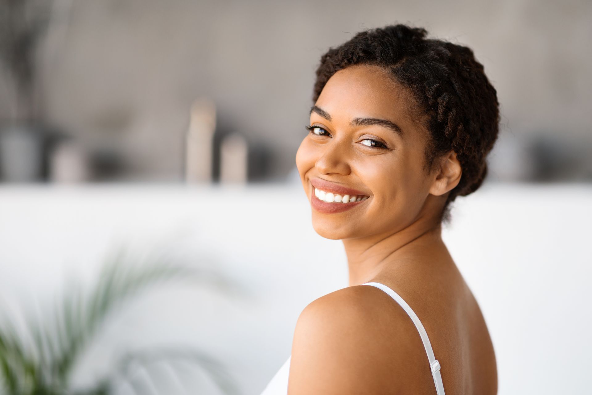 A woman is smiling and looking over her shoulder at the camera.