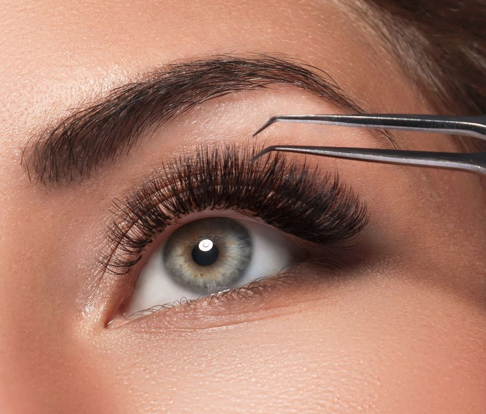A woman is getting her eyebrows done with tweezers.