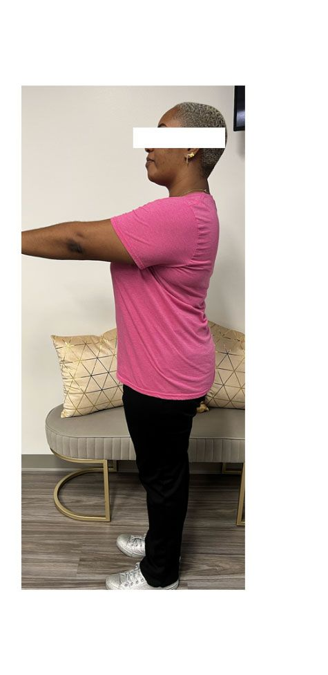 Person wearing a pink shirt and black pants standing next to a bench with pillows.