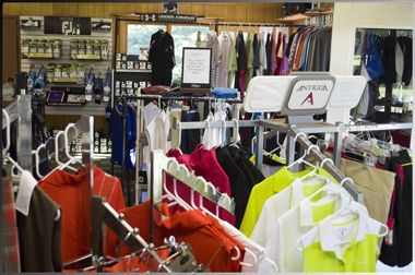 A well-stocked golf pro shop featuring rows of apparel on hangers, including bright orange, yellow, and black garments.