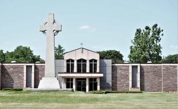 Modern church building with a tall cross monument in front and a landscaped lawn