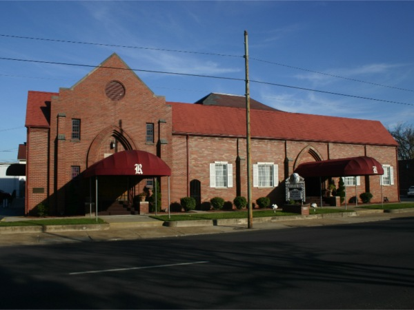 A brick building with a red awning that says k on it