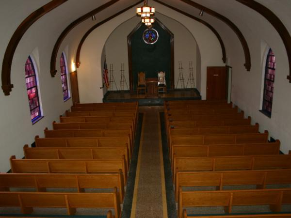 A church with rows of wooden benches and stained glass windows