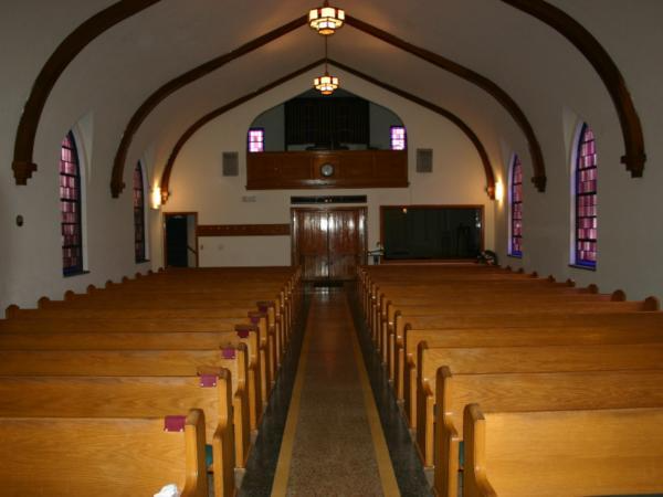 A church with rows of wooden benches and stained glass windows