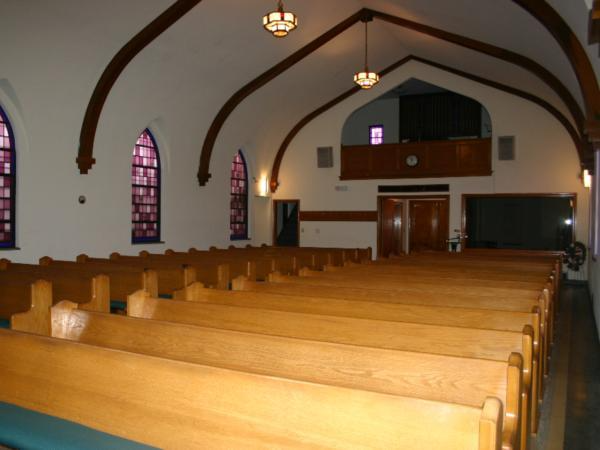A church with rows of wooden benches and stained glass windows
