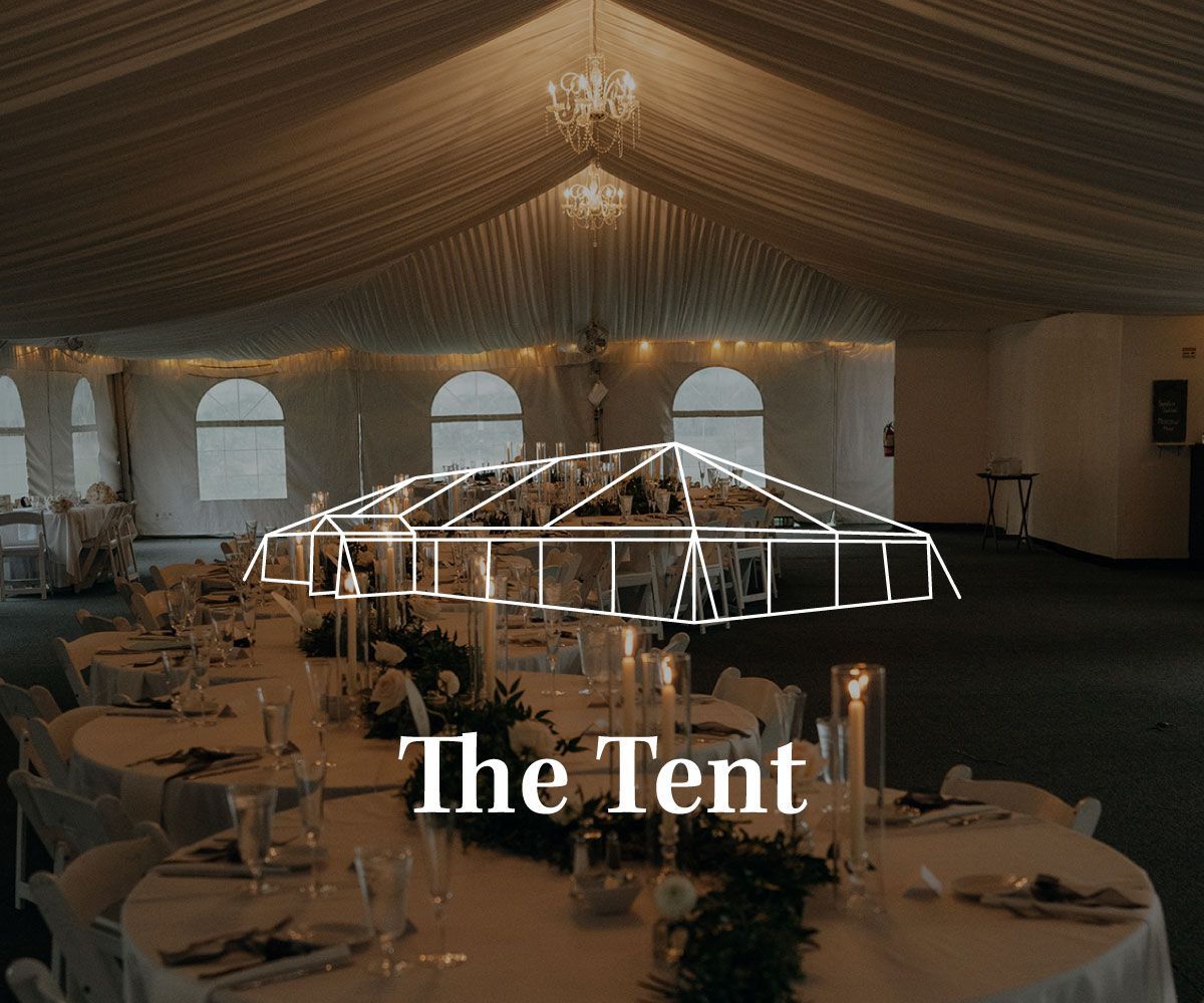 A draped event tent interior with round tables, white tablecloths, and floral centerpieces set for a formal gathering.