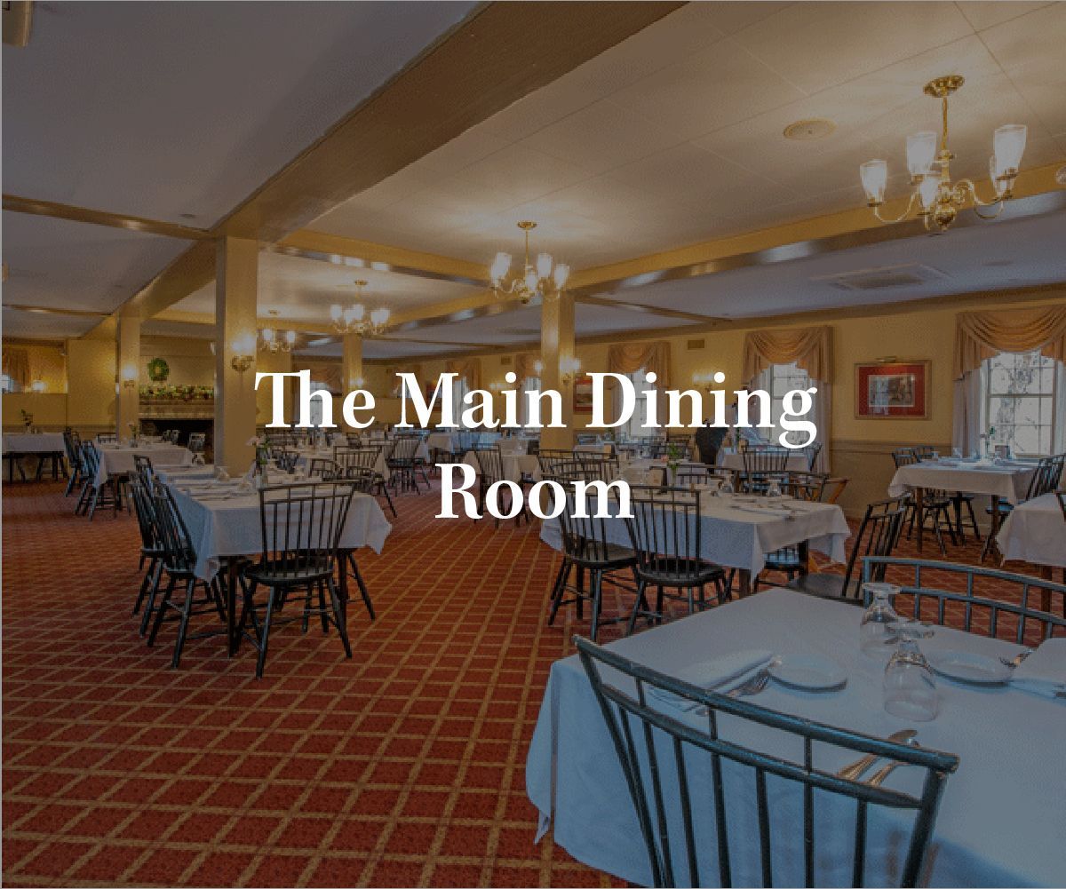 Spacious dining room with white-clothed tables, wooden chairs, and red patterned carpet under warm overhead lighting.