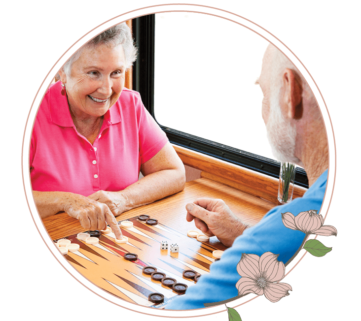 A man and a woman playing a game of backgammon at a local senior living community