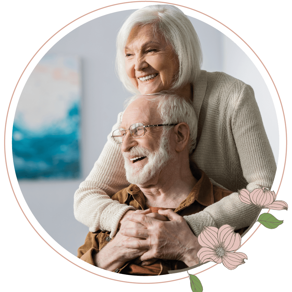 An elderly woman hugging an elderly man in a wheelchair 