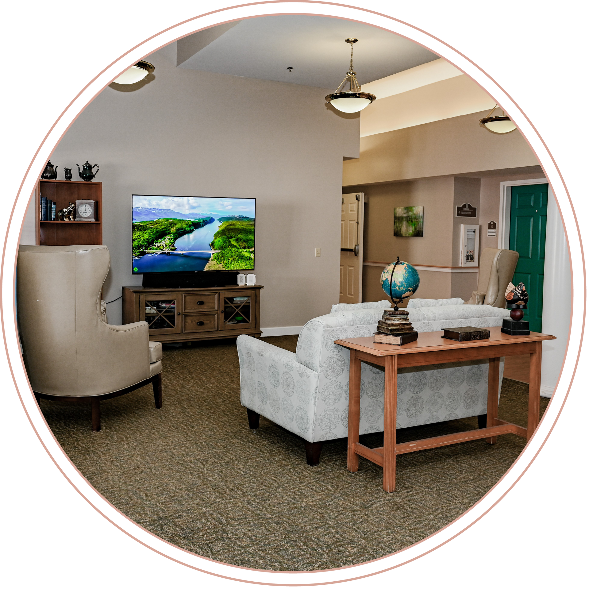A living room with a couch, a chair, and a flat screen TV at a local Memory Care Facility