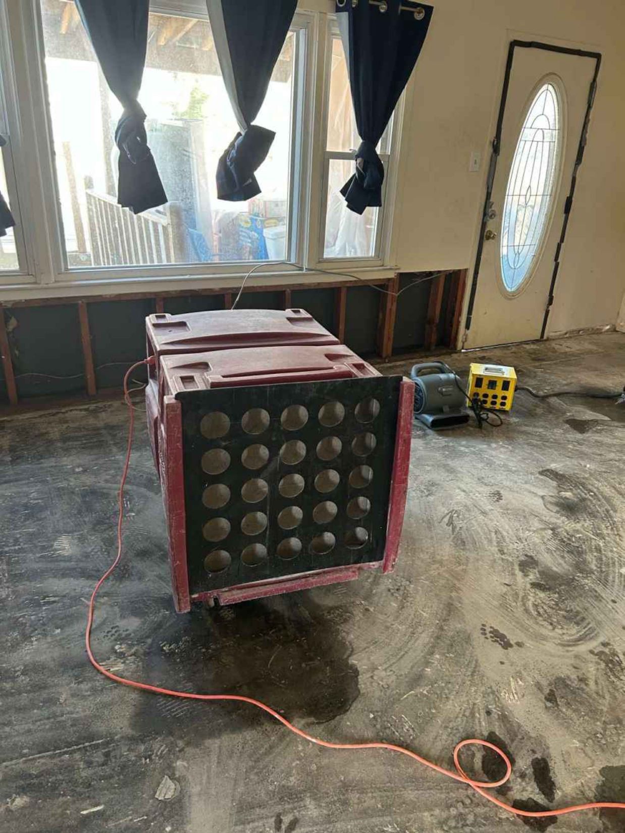 Large red speaker cabinet in a room under renovation, with cords on the floor and windows in the background