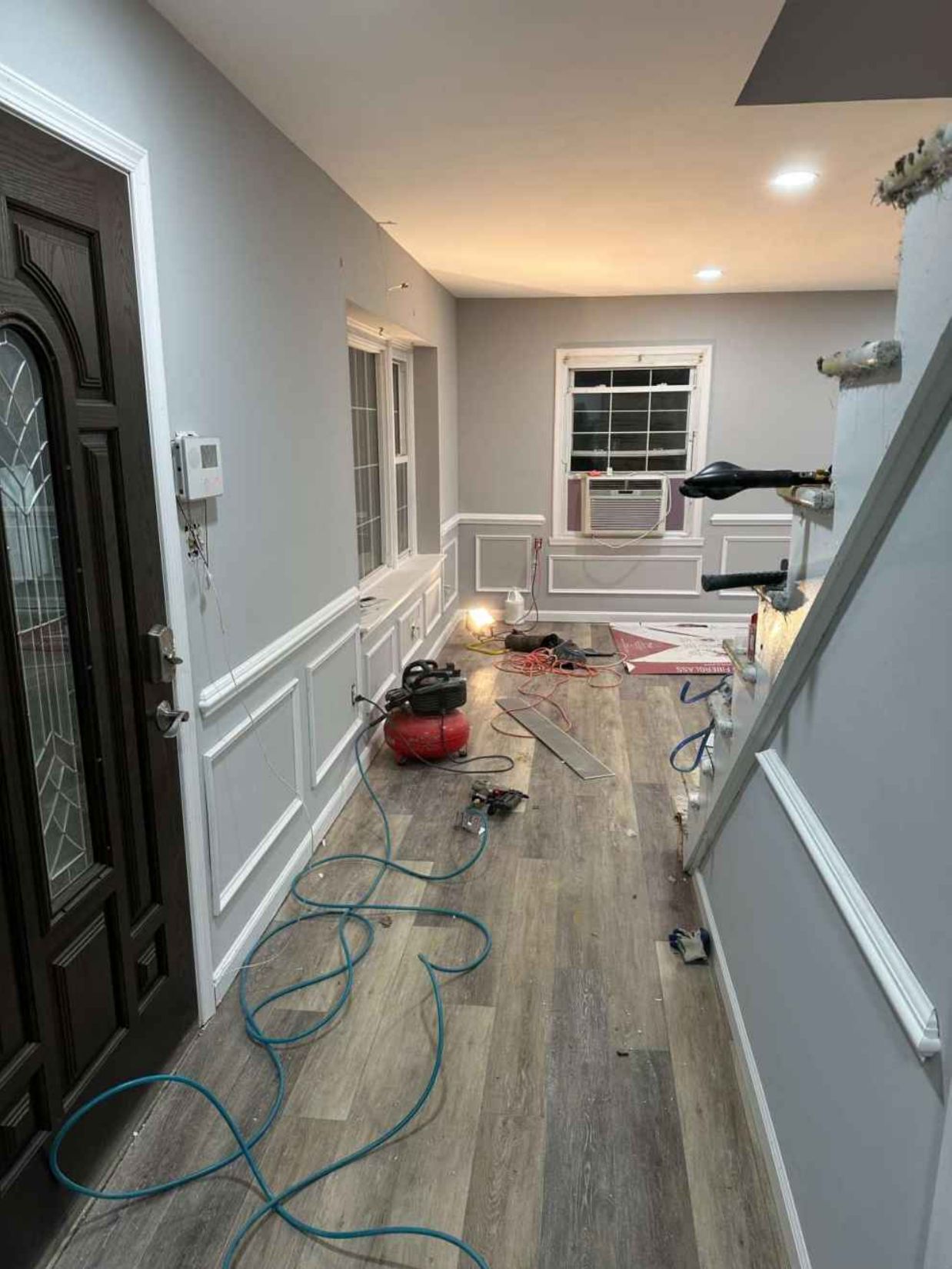 Hallway under renovation with tools, extension cords, and protective floor covering