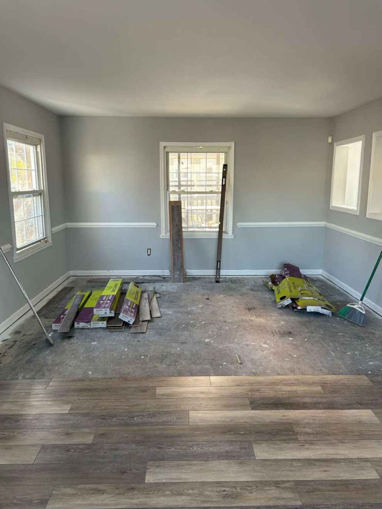 Partially renovated room with gray walls, new flooring, and construction materials on the floor