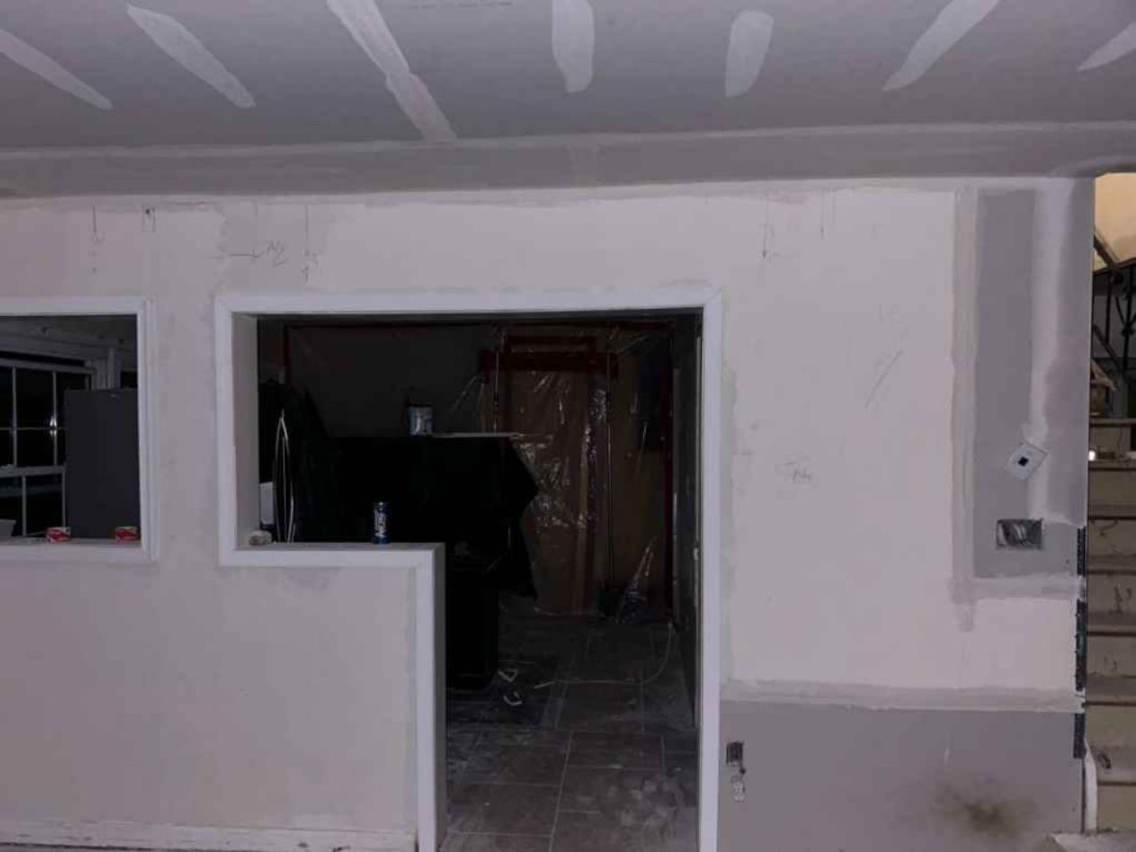 Partially constructed house exterior with open doorway and windows, showing unfinished interior