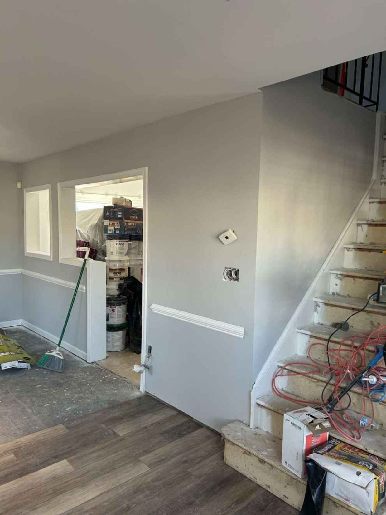 Unfinished interior with gray walls, exposed stairs, and tools scattered on the floor.