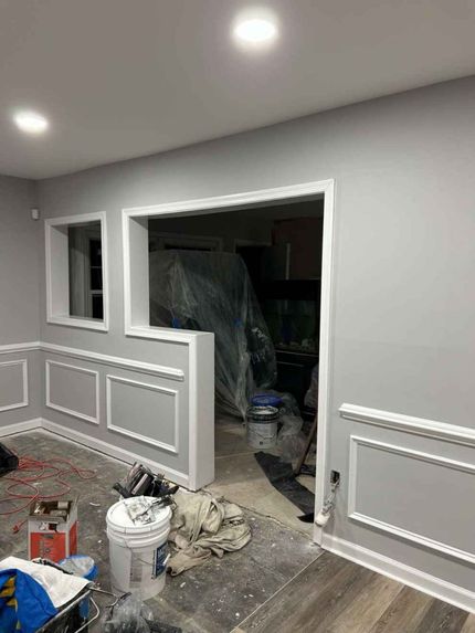 Empty hallway room with white walls, gray floors, and renovation tools and boxes along the sides