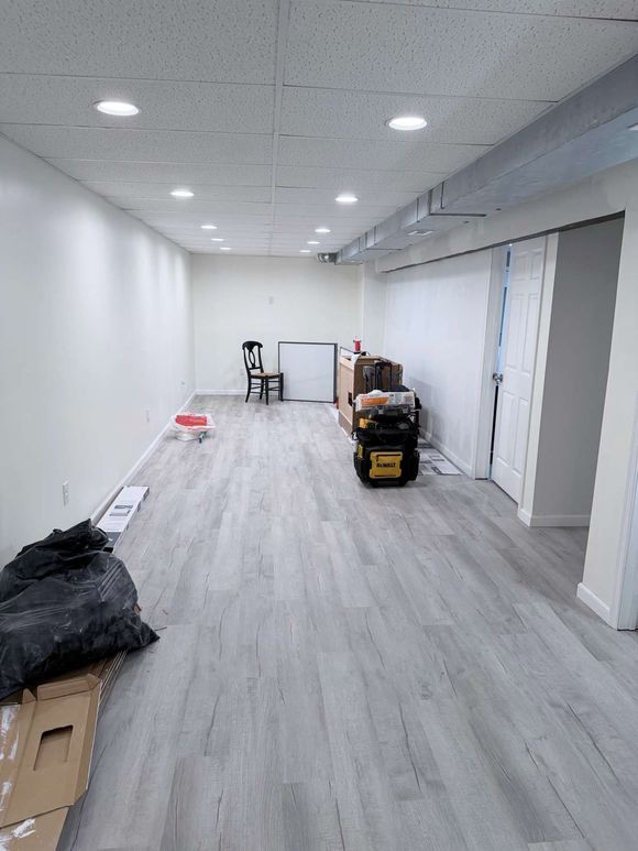 Empty hallway room with white walls, gray floors, and renovation tools and boxes along the sides