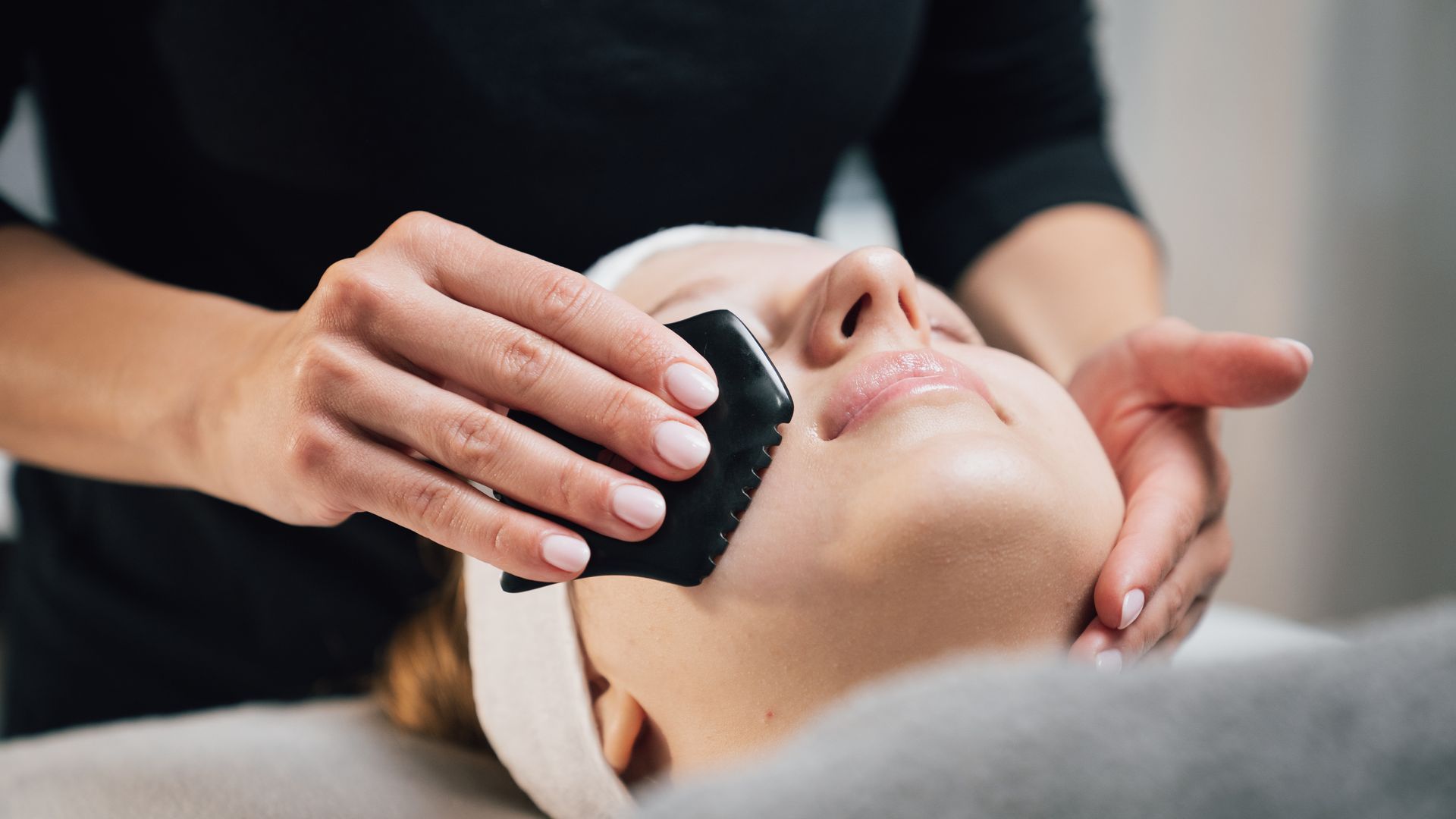 Gesichtsbehandlung mit einem Pinsel, der auf das Gesicht einer liegenden Person in einer Spa-Umgebung aufgetragen wird