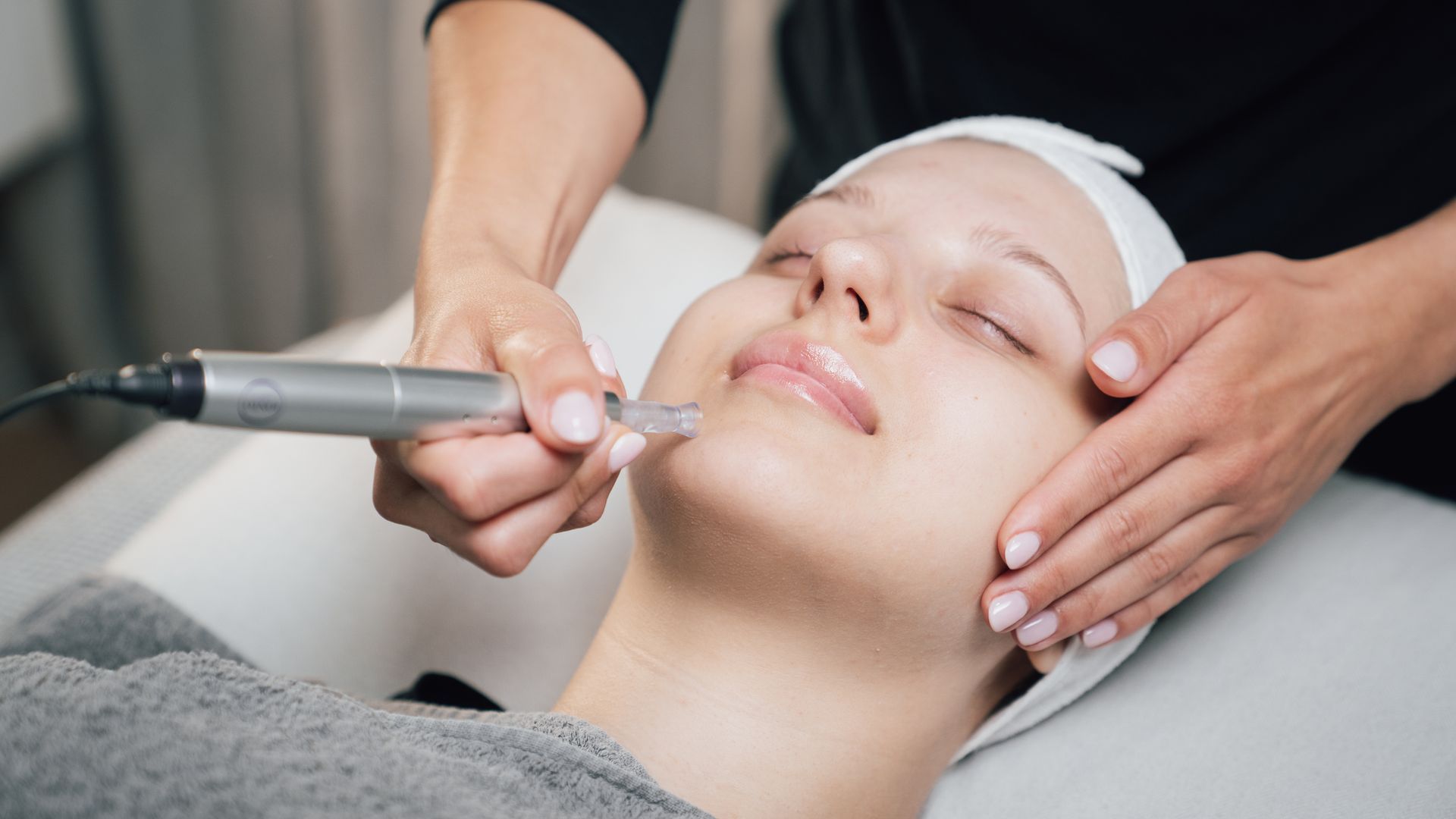 Gesichtsbehandlung mit einem Handgerät an einem liegenden Kunden in einem Spa