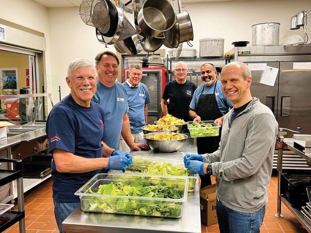 A group of men are preparing food in a kitchen.