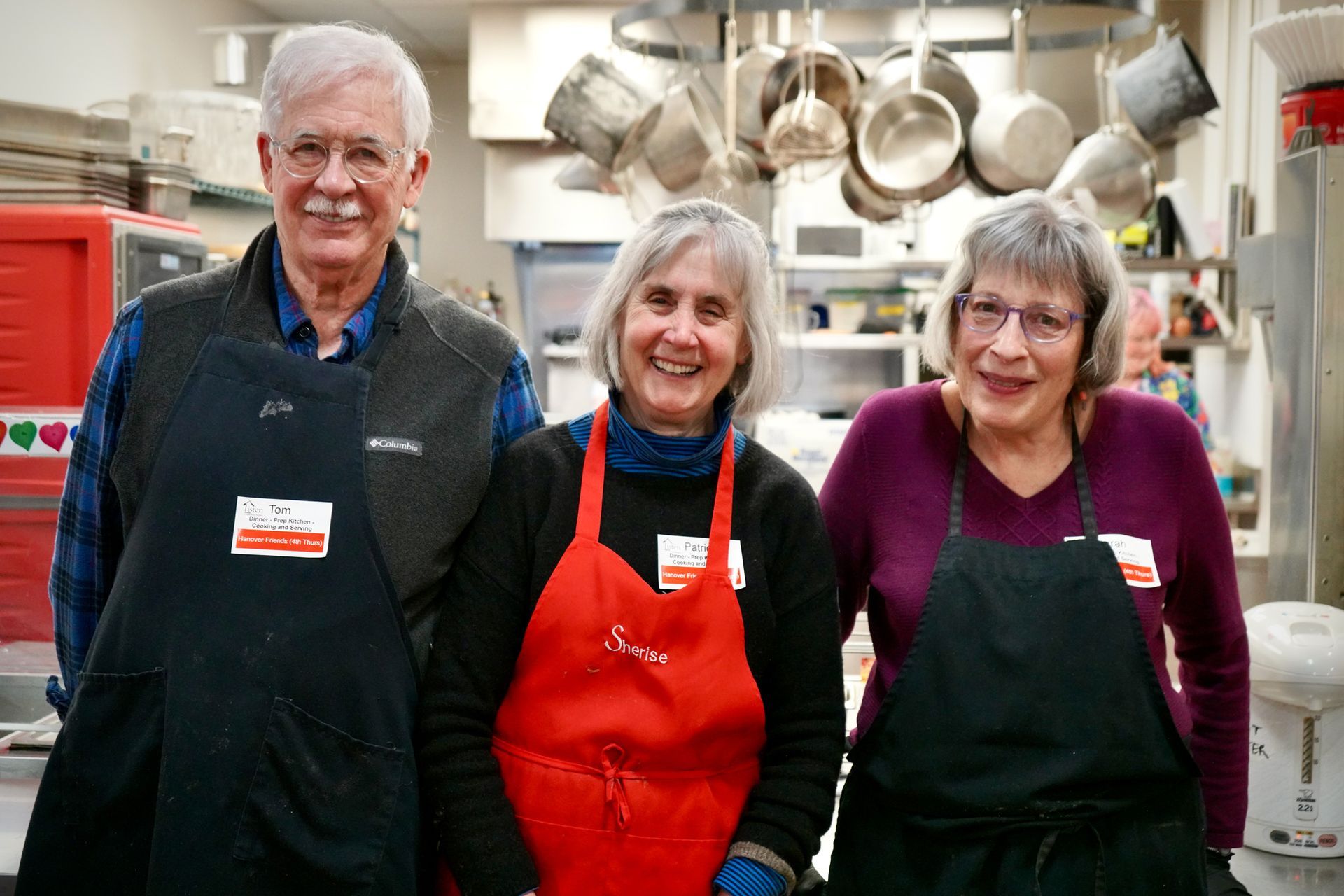 A man and two women are posing for a picture in a kitchen.