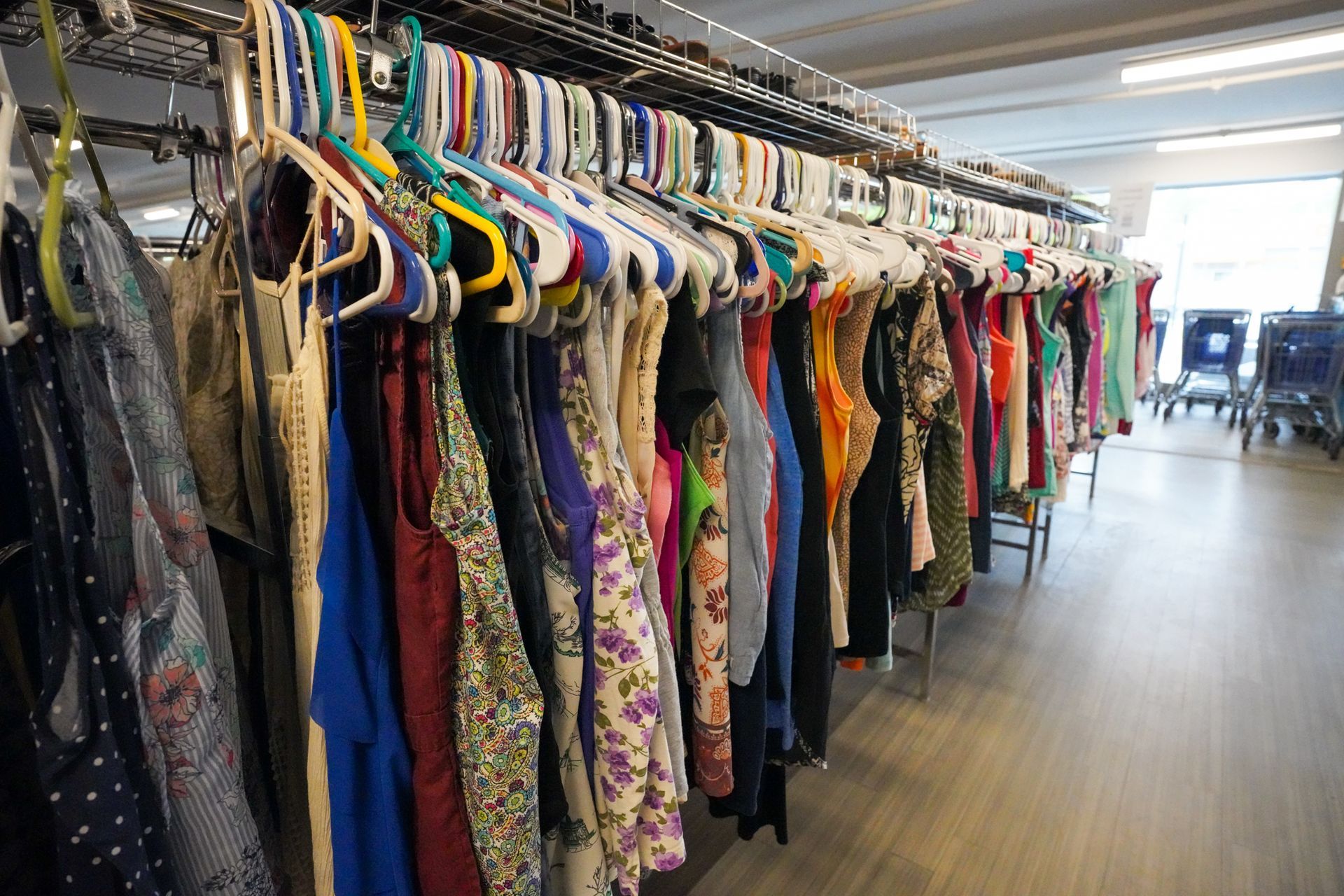A row of clothes hanging on racks in a store.