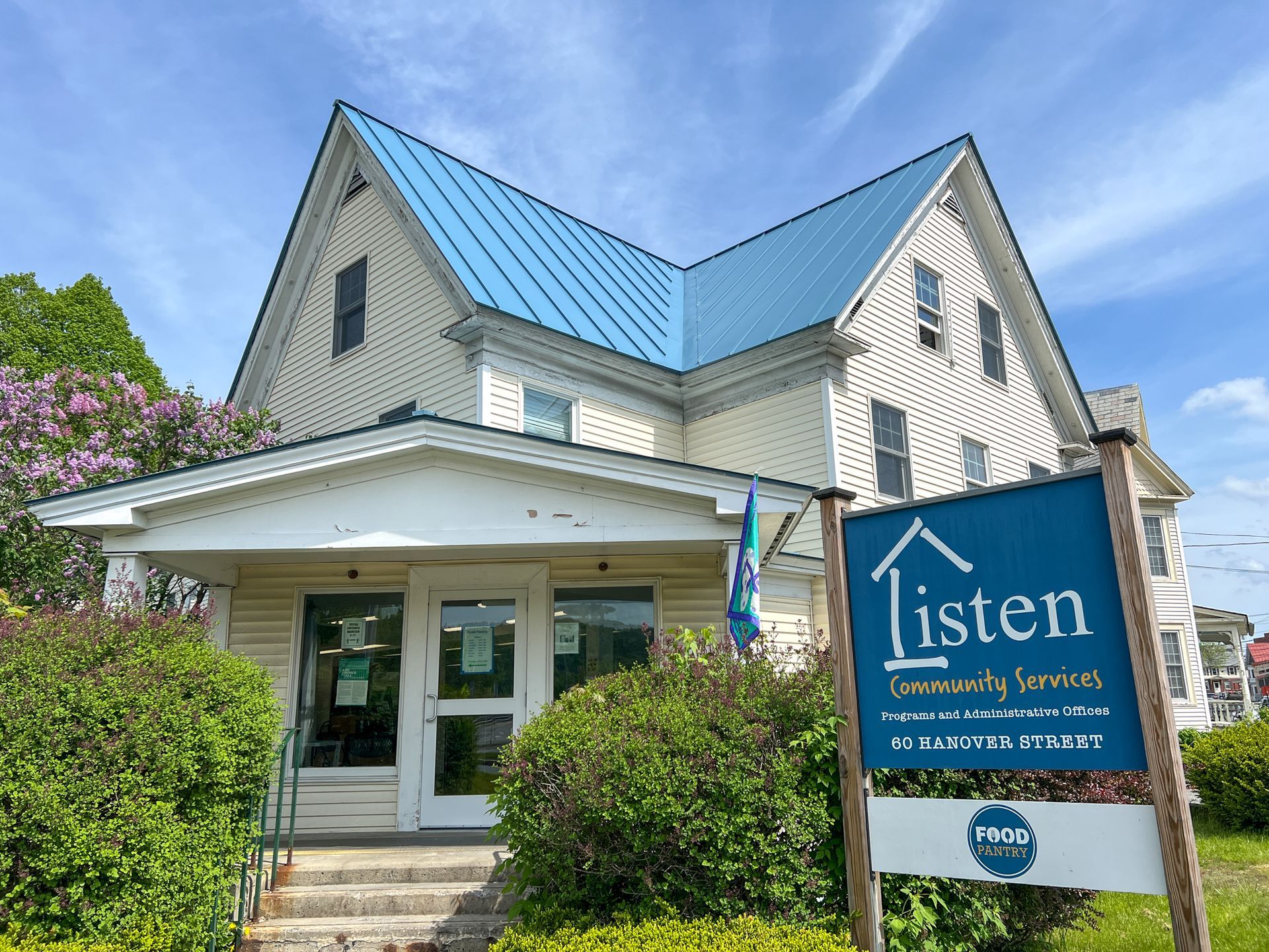 A white house with a blue roof and a listen sign in front of it.