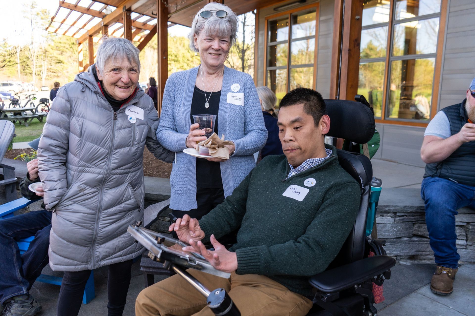 A man in a wheelchair is standing next to two women.
