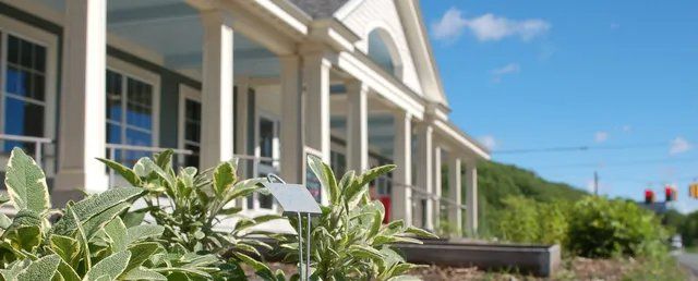 A white house with a porch and a sign in front of it