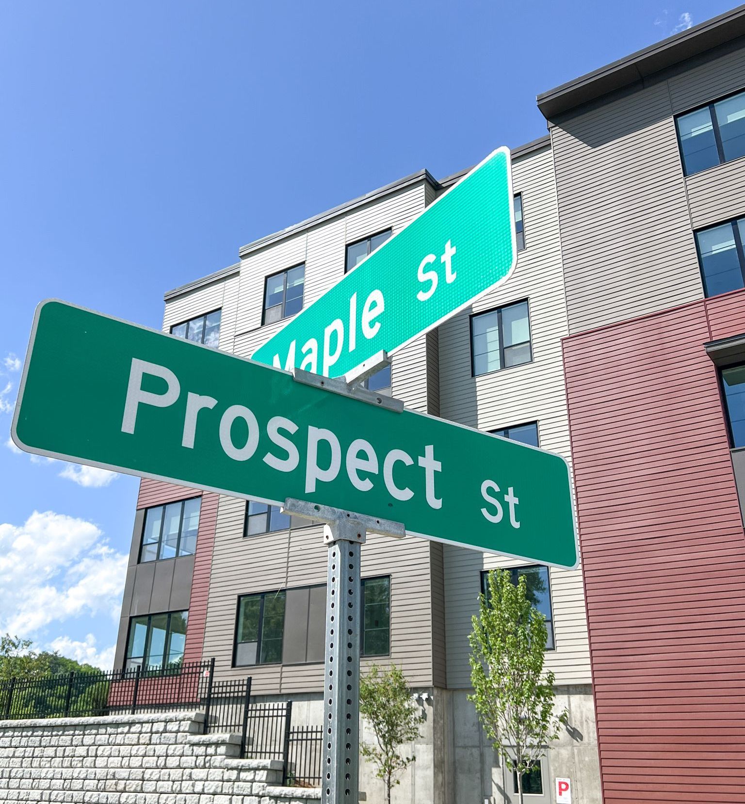 A green street sign for prospect st. and maple st.