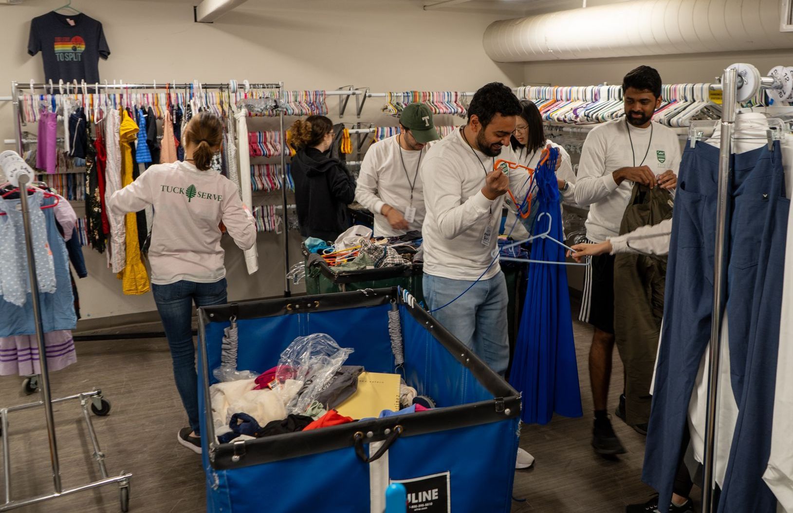 A group of people are standing around a cart filled with clothes.