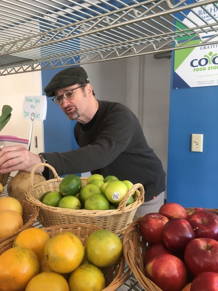 A man is standing in front of baskets of fruit and vegetables.