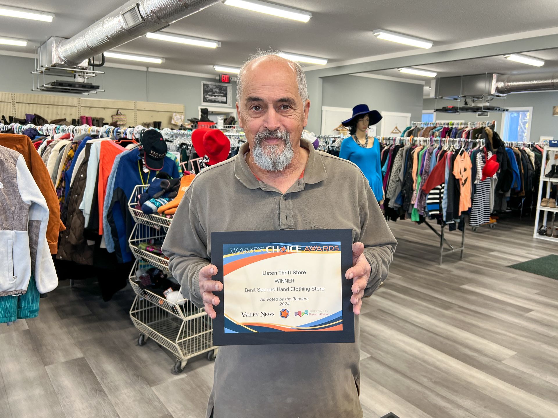 A man is holding a certificate in a thrift store.