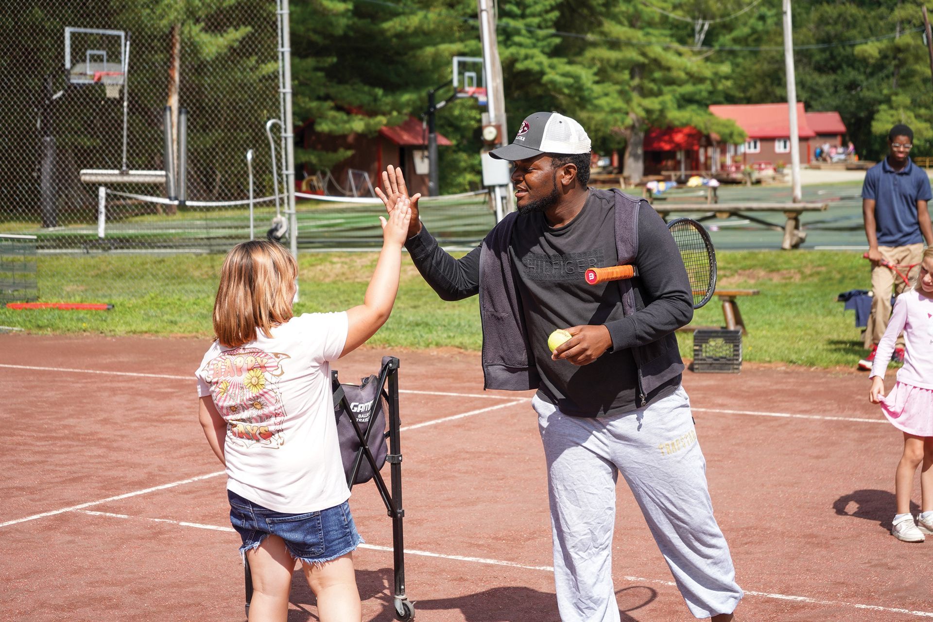 A man is giving a girl a high five on a tennis court.