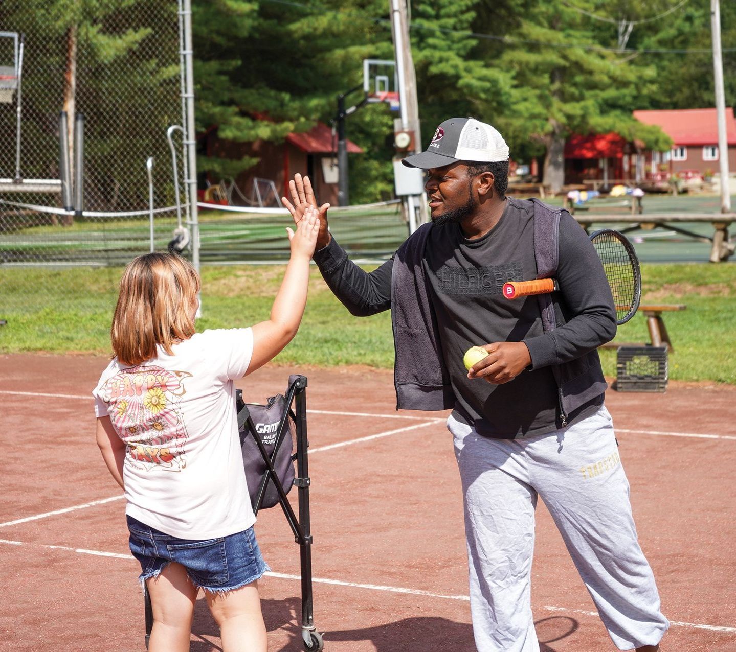 A man giving a girl a high five on a tennis court