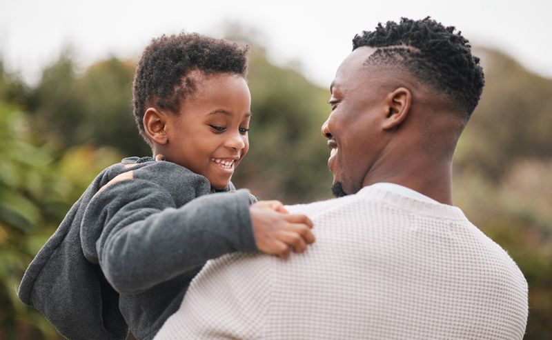A man is holding a little boy on his shoulders.