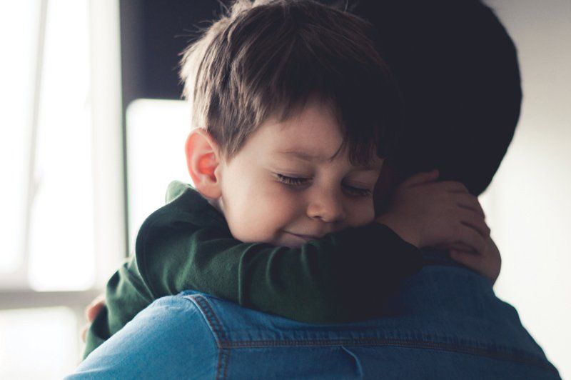 A young boy is hugging his father.